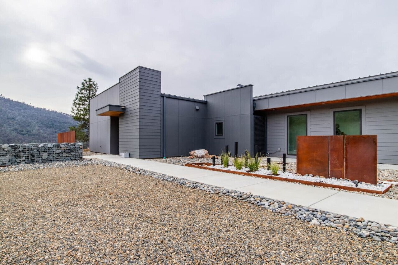 Un bâtiment moderne doté d’un toit plat, d’un chemin en béton et d’une zone recouverte de gravier.