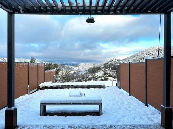 Un espacio al aire libre cubierto de nieve con un banco y una lámpara colgante.