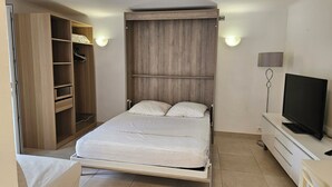 Een slaapkamer met een bed, een kledingkast, een televisie en een lamp.
