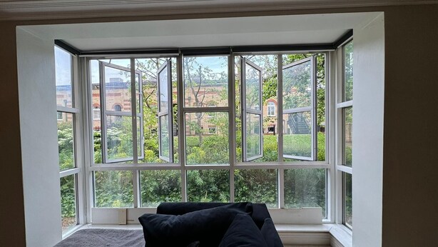 A room with a large bay window overlooking a garden and buildings. - Luxury Apartment In London - Pool Spa & Gym (London)
