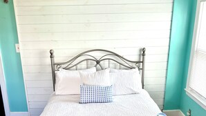 A neatly made bed with a metal frame, white bedding, and a blue and white patterned pillow. - Ocean view, private 4 Bedroom home just steps to the beach! (Old Orchard Beach)