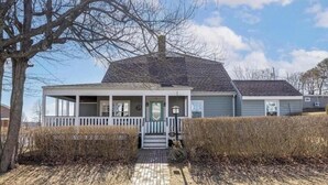 A two-story house with a front porch, a chimney, and a brick pathway leading to the entrance. - Ocean view, private 4 Bedroom home just steps to the beach! (Old Orchard Beach)