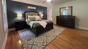 A bedroom with a bed, nightstands, a dresser, a ceiling fan, and a rug. - Cozy 3BR Getaway, Lake access, Fire Pit, Trails (Mount Airy)