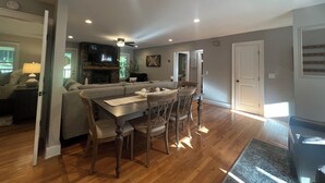 A spacious living room with a fireplace, a dining area with a wooden table and chairs, and a cozy seating area with a sofa. - Cozy 3BR Getaway, Lake access, Fire Pit, Trails (Mount Airy)