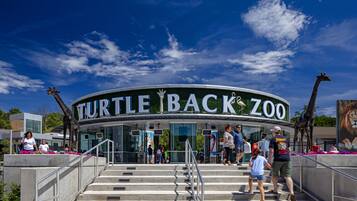 The entrance to the Turtle Back Zoo with a curved glass facade and a sign above the entrance.