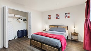 Un dormitorio con una cama de madera, un armario, una mesita de noche y una mesilla.