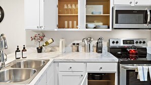 Una cocina moderna con muebles blancos, horno empotrado y lavavajillas.