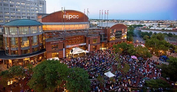 A large convention center with a prominent 'nipac' sign, multiple levels, and a crowd gathered outside.