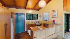 Una cocina con armarios de madera, estufa, refrigerador y ventana con vista a la vegetación.