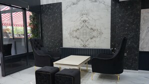 A modern lounge area with black upholstered chairs, a white table, and black marble-patterned ottomans. - ETAP BULVAR HOTEL (Ankara)