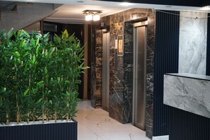 A modern elevator area with marble walls and a reception desk. - ETAP BULVAR HOTEL (Ankara)