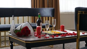 A dining table with a bouquet of red roses, a bottle of wine, two glasses, a candle, and a plate of fruit. - ETAP BULVAR HOTEL (Ankara)