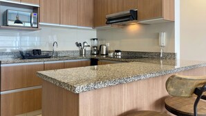 Una cocina moderna con armarios de madera, encimeras de granito, microondas integrado, cafetera y teléfono.