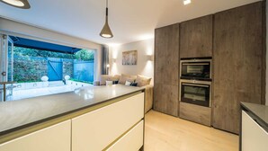 A modern kitchen with a large island, built-in ovens, and a view of the backyard. - The Nothinghill Charmer (London)