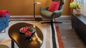 A modern living room with a green armchair, a black coffee table with fruit, and a wall-mounted floor lamp. - Lucky Cranes (Bucharest)