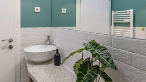 A bathroom with a white sink, a mirror, teal walls, and a potted plant. - Lucky Cranes (Bucharest)