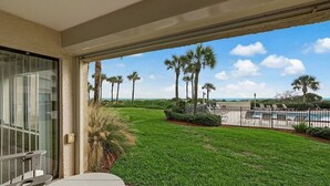 Un balcon avec vue sur une piscine, des palmiers et un ciel dégagé.