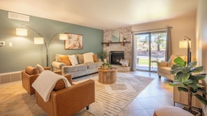 A living room with a fireplace, a sofa set, a coffee table, and a large window with a view of the outdoors. - 3 Bedrooms, Sleeps 7, Pool/Spa, Tennis/Pickleball, Red Rock Views, Restaurants  (Sedona)