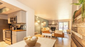 A modern kitchen with stainless steel appliances, a dining area with a wooden table and a bowl of bread, and a living room with a fireplace and comfortable seating. - 3 Bedrooms, Sleeps 7, Pool/Spa, Tennis/Pickleball, Red Rock Views, Restaurants  (Sedona)