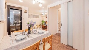 A dining area with a table set for four, wooden chairs, and a vase with flowers.