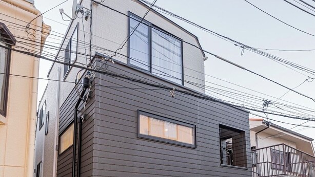 A modern two-story house with a dark grey exterior, a small balcony, and a visible mailbox.
