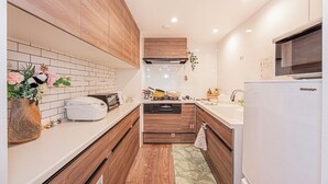 A modern kitchen with wooden cabinets, a white countertop, a built-in oven, and a refrigerator.