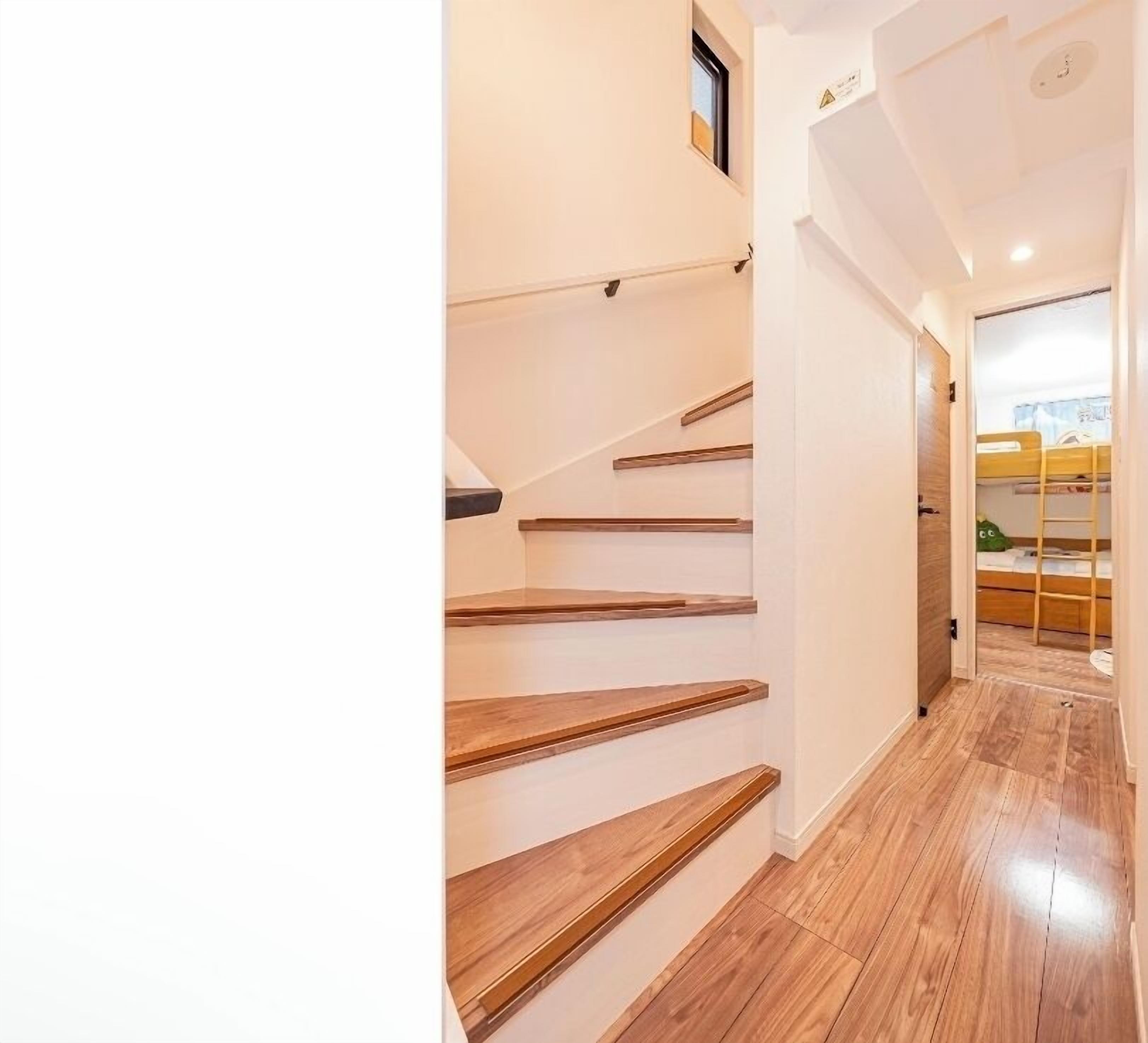A staircase with wooden steps leading to a room with a bunk bed.