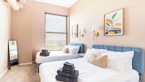 A hotel room with two beds, a large window with blinds, and artwork on the walls. - Cleveland Loft-Wolstein/Progressive/Playhouse/CSU. (Cleveland)