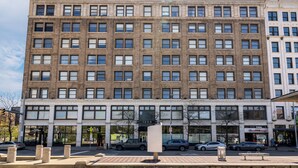 A multi-story building with a brick facade, large windows, and storefronts at the ground level. - Cleveland Loft-Wolstein/Progressive/Playhouse/CSU. (Cleveland)
