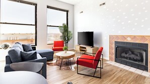 A modern living room with a sofa, red chairs, a TV, a fireplace, and large windows. - Cleveland Loft-Wolstein/Progressive/Playhouse/CSU. (Cleveland)