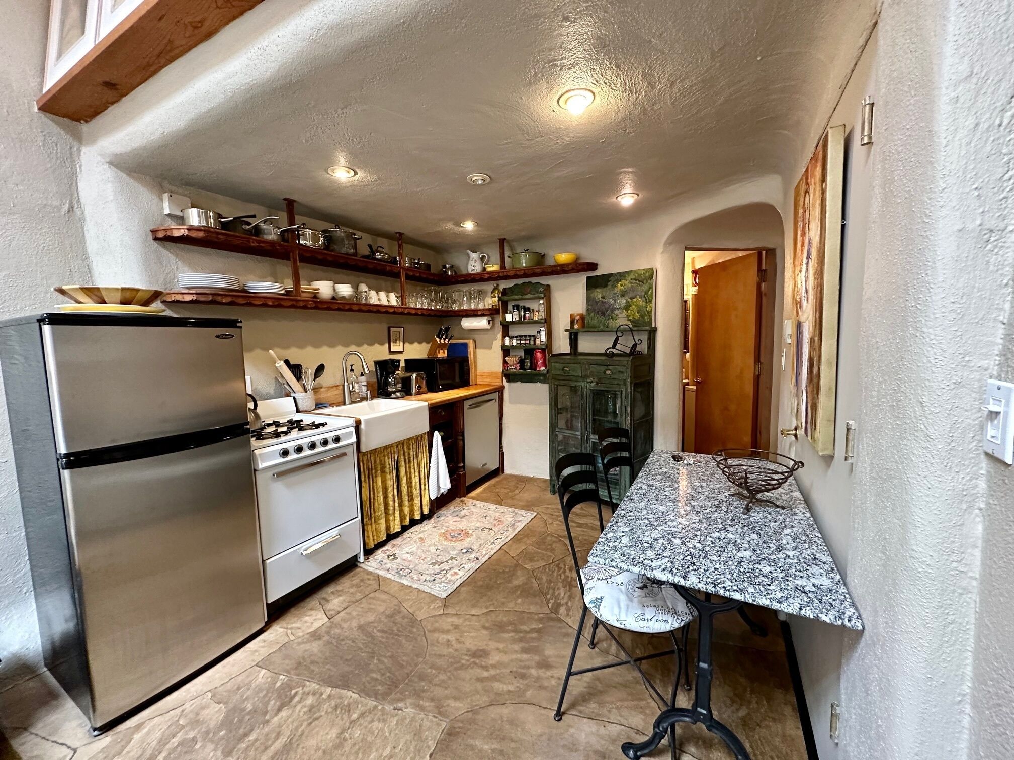 A compact kitchen with a refrigerator, stove, sink, and a dining area with a table and chairs.