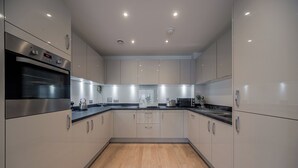 A modern kitchen with stainless steel appliances, wooden flooring, and recessed lighting. - Barking Bright Apartment With 2 Bedrooms (Barking)