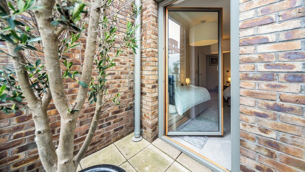 A brick exterior wall with a sliding glass door leading to a bedroom. - Barking Bright Apartment With 2 Bedrooms (Barking)