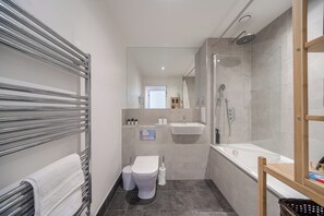 A modern bathroom with a shower, toilet, sink, and towel rack.