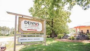 A sign for Dennis Vineyards with a tasting room and gift shop, and a curbside service sign.