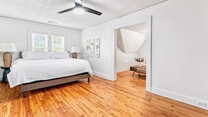 A bedroom with a bed, two bedside tables, a ceiling fan, and a window with blinds.