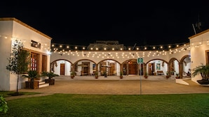 Un patio con un edificio que presenta paseos con arcos e iluminación de luces.