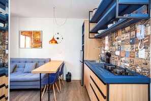 A compact kitchen with a wooden countertop, a built-in stove, and a wall of vintage posters.