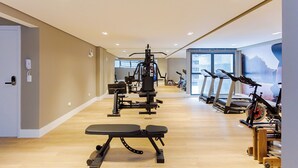 Un gimnasio con equipamiento de ejercicio, cintas de correr y una banca.