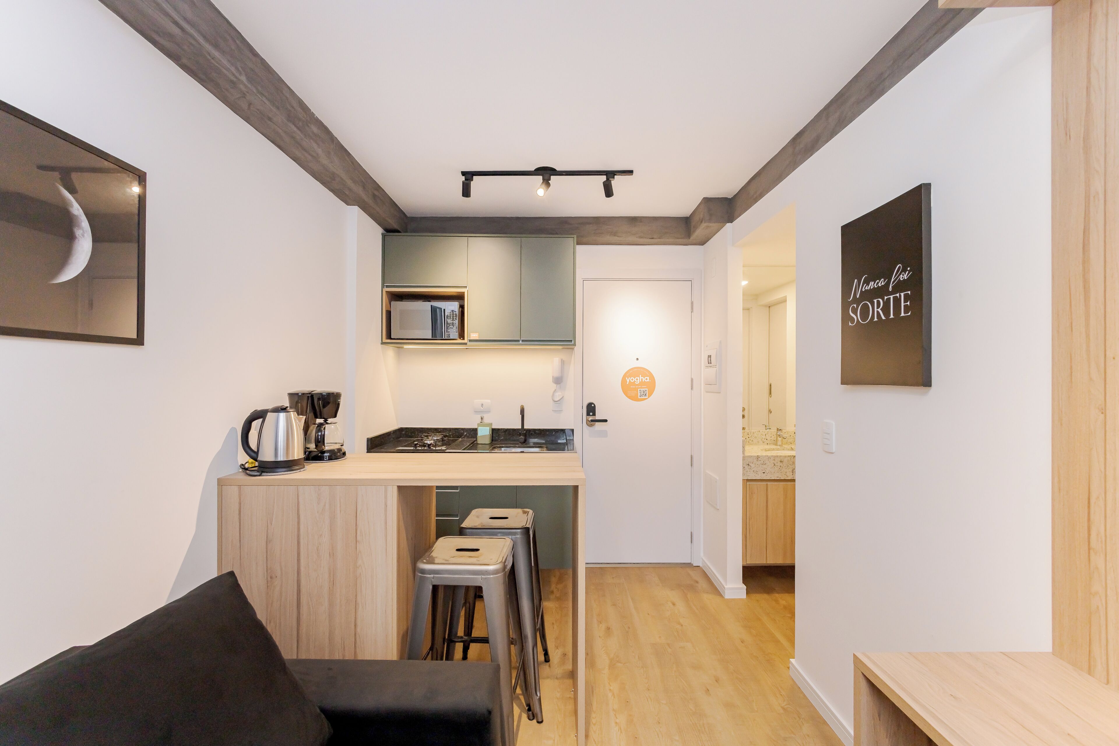 A compact living space with a kitchenette, a small dining area, and a bar stool.