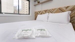 Habitación de hotel con cama, dos almohadas, una ventana y dos jabones individuales.