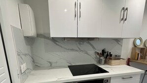 Eine moderne Küche mit weißen Schränken, einem eingebauten Geschirrspüler und einer schwarzen Induktionskochplatte.