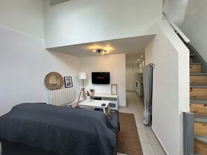 A modern bedroom with a bed, a desk, a TV, and a staircase.