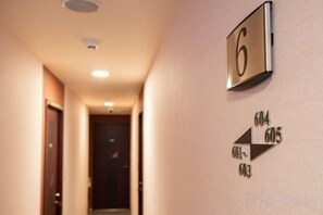 Passadís amb un senyal indicador de número de habitació, el 6, i fletxes direccionals que apunten a les habitacions 604, 605 i 603.