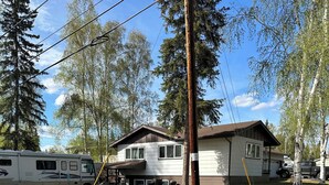 A two-story house with a front porch, a driveway, and a parked RV.