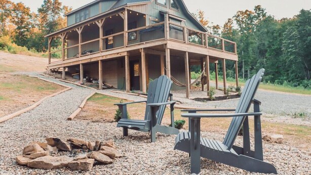 A cabin with a porch, two Adirondack chairs, and a fire pit. - Peaceful Hocking Hills Cabin | Hot Tub! Fireplace! (South Bloomingville)