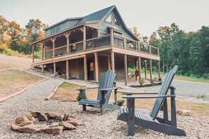 A cabin with a porch, two Adirondack chairs, and a fire pit. - Peaceful Hocking Hills Cabin | Hot Tub! Fireplace! (South Bloomingville)