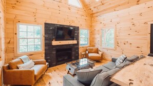 A cozy cabin interior with a fireplace, wooden walls, and a sofa set. - Peaceful Hocking Hills Cabin | Hot Tub! Fireplace! (South Bloomingville)