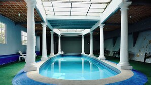 An indoor swimming pool with white columns, green artificial turf, and a tiled ceiling. - Hotel El Castillo (Cuernavaca)