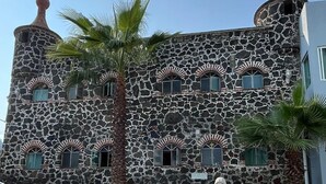 A building with a stone facade, arched windows, and a statue in the courtyard. - Hotel El Castillo (Cuernavaca)